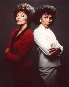 two women standing next to each other in front of a black background with their arms crossed