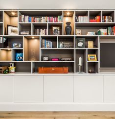 a book shelf filled with lots of books on top of white shelves next to a wooden floor