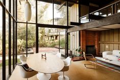 a living room filled with furniture and a fire place next to a wall covered in windows