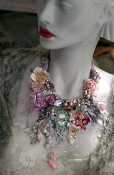 a white mannequin wearing a multicolored necklace with flowers on it's neck