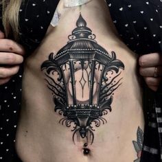 a woman's stomach with a lantern tattoo on her belly and the light is lit up