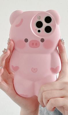 a woman holding up a pink phone case with a pig design on the front and side