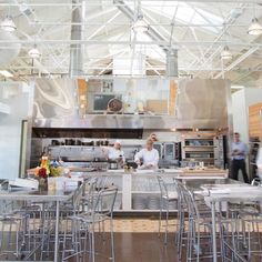 blurry photograph of people working in a commercial kitchen with stainless steel tables and stools