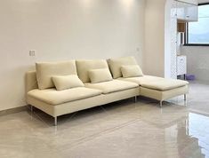 a white couch sitting in the middle of a living room next to a large window