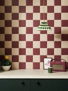 a lamp hanging over a kitchen counter next to a potted plant and a radio