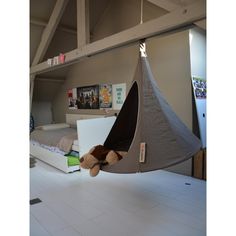 a teddy bear is sitting in a hammock hanging from the ceiling over a bed