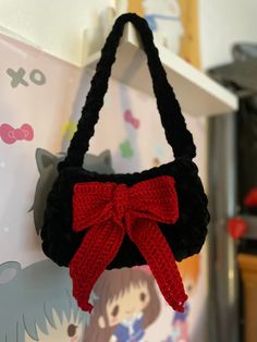 a crocheted purse with a red bow hanging from it's front end