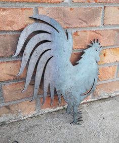 a metal rooster standing next to a brick wall