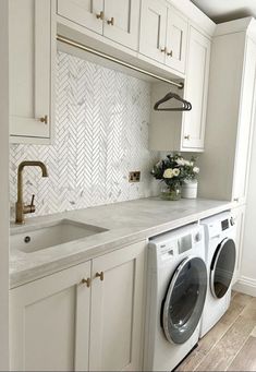 a washer and dryer in a white kitchen with herringbone backsplash