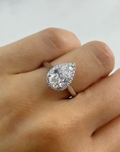 a woman's hand with a diamond ring on top of her finger and an engagement ring in the middle