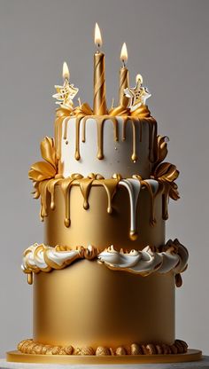 a three tiered cake with gold icing and lit candles on the top layer