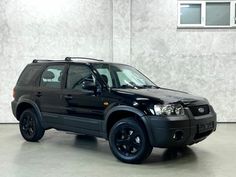 a black suv parked in front of a white wall