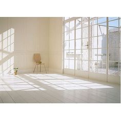 an empty room with large windows and a chair