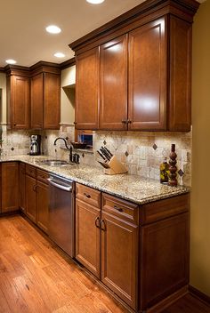 a large kitchen with wooden cabinets and granite counter tops, along with hardwood flooring