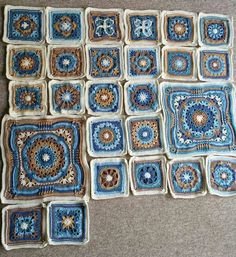 crocheted squares are arranged on the floor in rows, with blue and brown designs