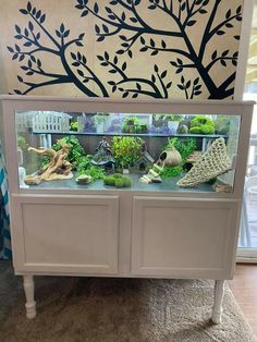 a fish tank is sitting on top of a cabinet in front of a wall painting