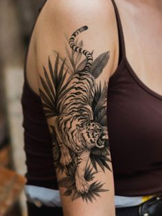 a woman's arm with a tiger and leaves tattoo on the left side of her arm