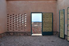 an open door leading into a room with stone walls and green shutters on the outside