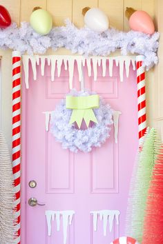 a pink door decorated with christmas decorations and candy canes