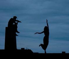 two people are silhouetted against the sky with their arms in the air