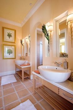 a bathroom with two sinks, mirrors and pictures on the wall above them is shown