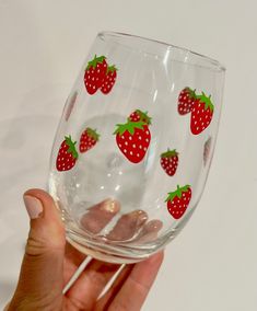 a hand holding a wine glass with strawberries on it