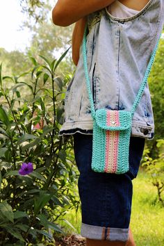 a woman is holding a crocheted purse in her hands while standing on the grass