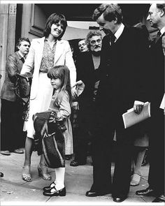 a group of people standing around each other on the side of a building with one woman holding her hand