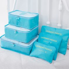 three blue luggage bags sitting on top of a bed next to pillows and a lamp