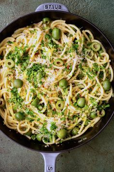 a skillet filled with pasta, olives and parmesan sprinkles