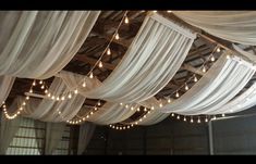 a room filled with lots of white drapes and string lights hanging from the ceiling