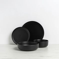 black dinnerware set on marble countertop against white wall, minimalistic styled design