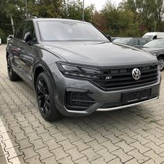 a grey volkswagen suv parked in a parking lot next to other cars on the street