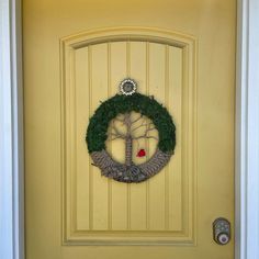 a yellow door with a green wreath on it and a red candle in the center