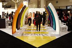 a group of people standing in front of a rainbow shaped display at a trade show