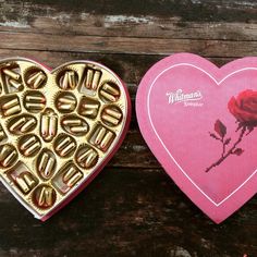 two heart shaped boxes filled with chocolates next to each other on top of a wooden table