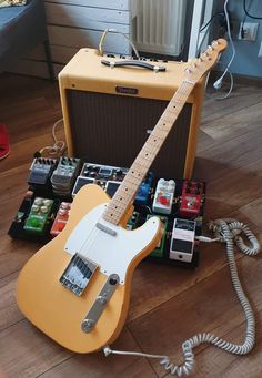 an electric guitar sitting on top of a hard wood floor next to some other musical equipment