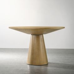 a wooden table sitting on top of a cement floor next to a white wall in an empty room