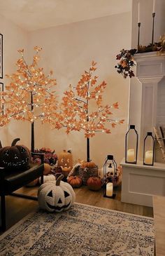 a living room decorated for halloween with pumpkins and trees on the wall, candles in front of them