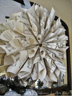 a large wreath made out of old sheet music paper is hanging on the wall in front of a mirror