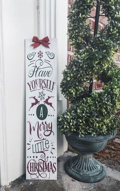 a sign that says have yourself a merry little christmas next to a potted plant