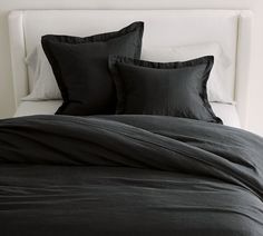 a bed with black linens and pillows on it