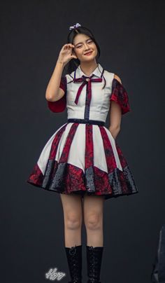 a woman in a red and white dress posing for the camera with her hands on her head