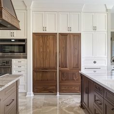 a large kitchen with white cabinets and marble counter tops, along with an island in the middle