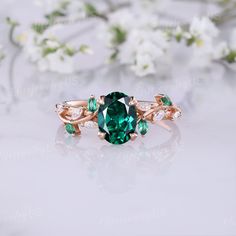 a green ring with leaves and stones on it's side, sitting next to white flowers