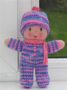 a small knitted doll sitting in front of a window