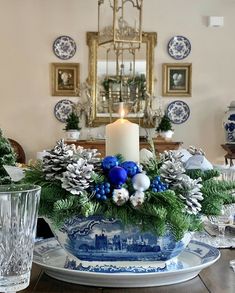 a blue and white christmas centerpiece on a dining room table with candlesticks