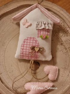 a small house made out of fabric on top of a wooden plate with pink and white decorations