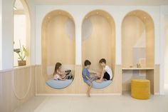 two children sitting on bean bags in the middle of a room with wooden walls and round windows