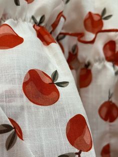 an apple print on white fabric with red and green leaves in the center, close up